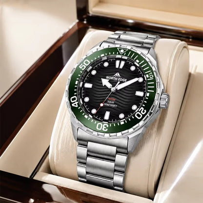 A stainless steel wristwatch with a green bezel and black dial, displayed inside a cream-colored watch box. The brand name NORTH EDGE is visible on the dial.